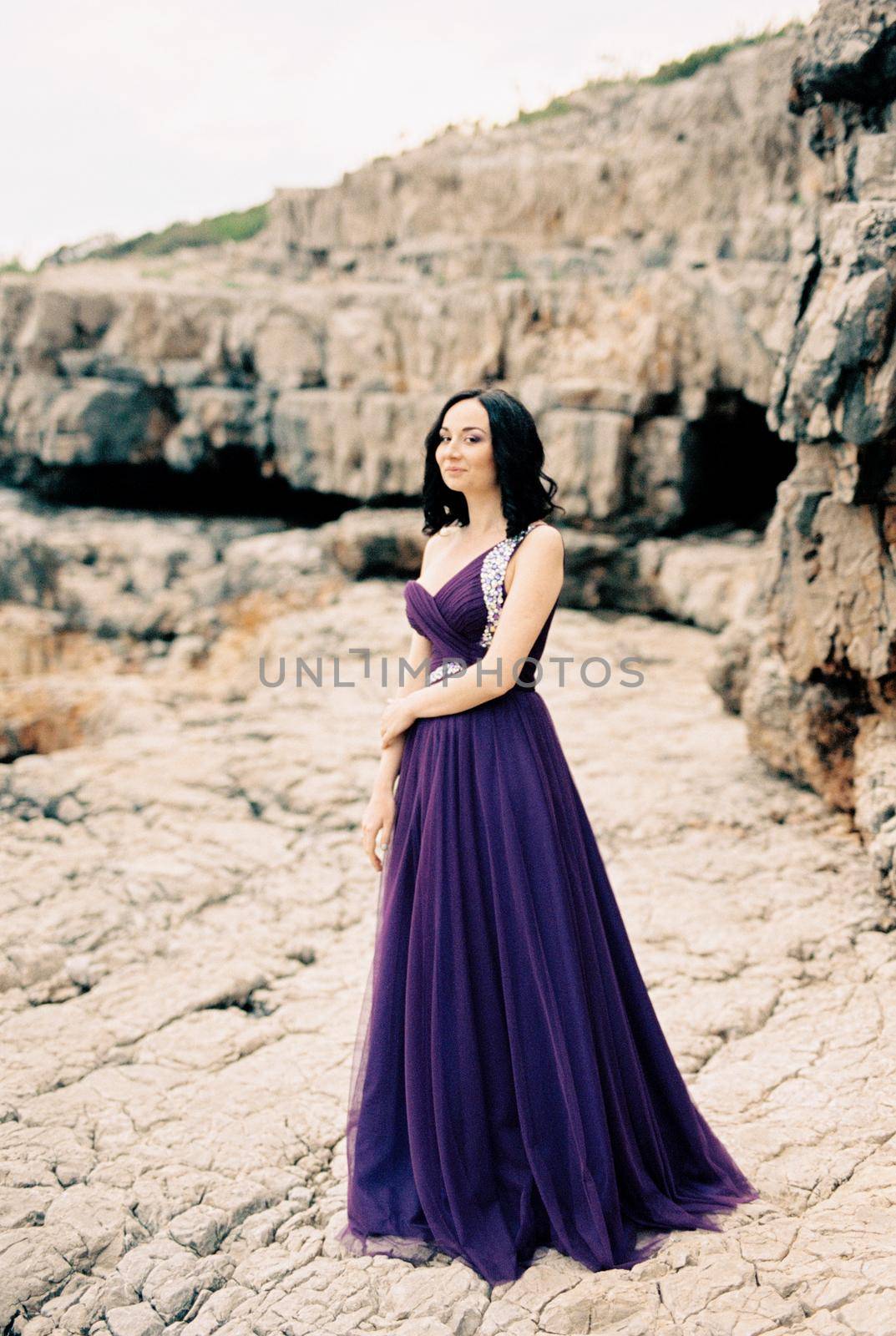 Woman in a long dress stands near the rocks. High quality photo