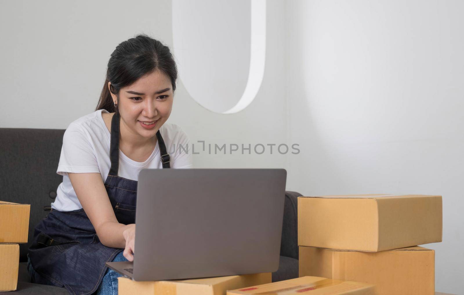 Starting Small business entrepreneur freelance,Portrait young woman working at home office, BOX,smartphone,laptop, online, marketing, packaging, delivery, SME, e-commerce concept.