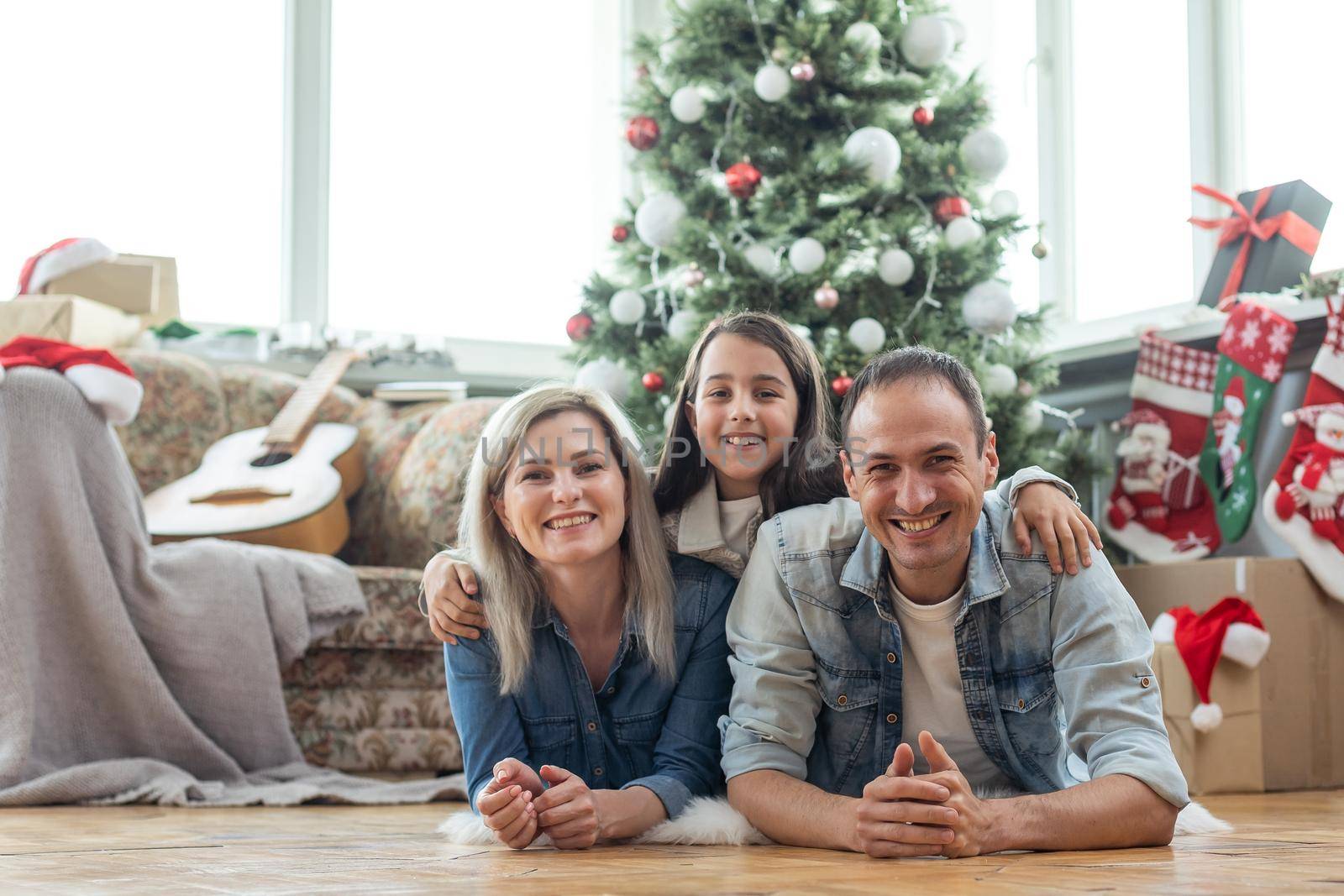 family having fun and playing together near Christmas tree indoors. by Andelov13