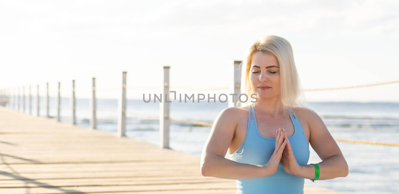 Woman doing yoga exercises by the sea. by Andelov13