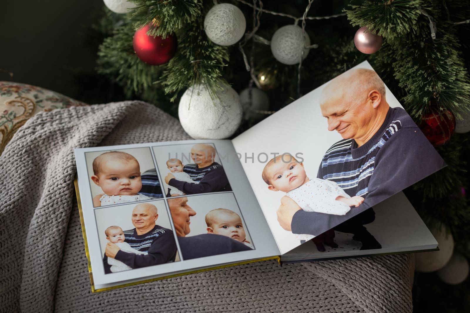 Photo book family photo album under the Christmas tree surrounded by Christmas gifts.