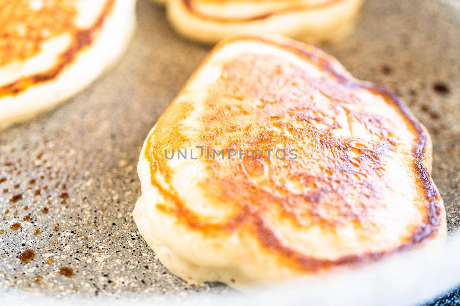 Frying kefir based pancakes in cooking pan on an electric stove.