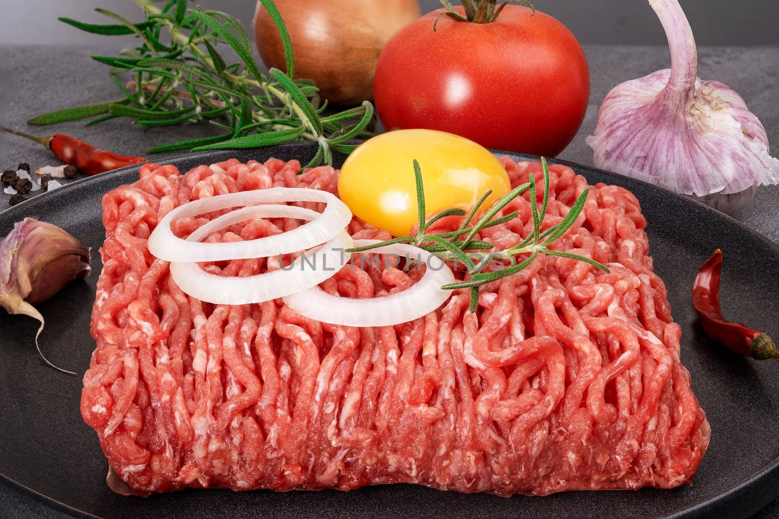 Minced meat lies on a black ceramic plate. Selective focus.