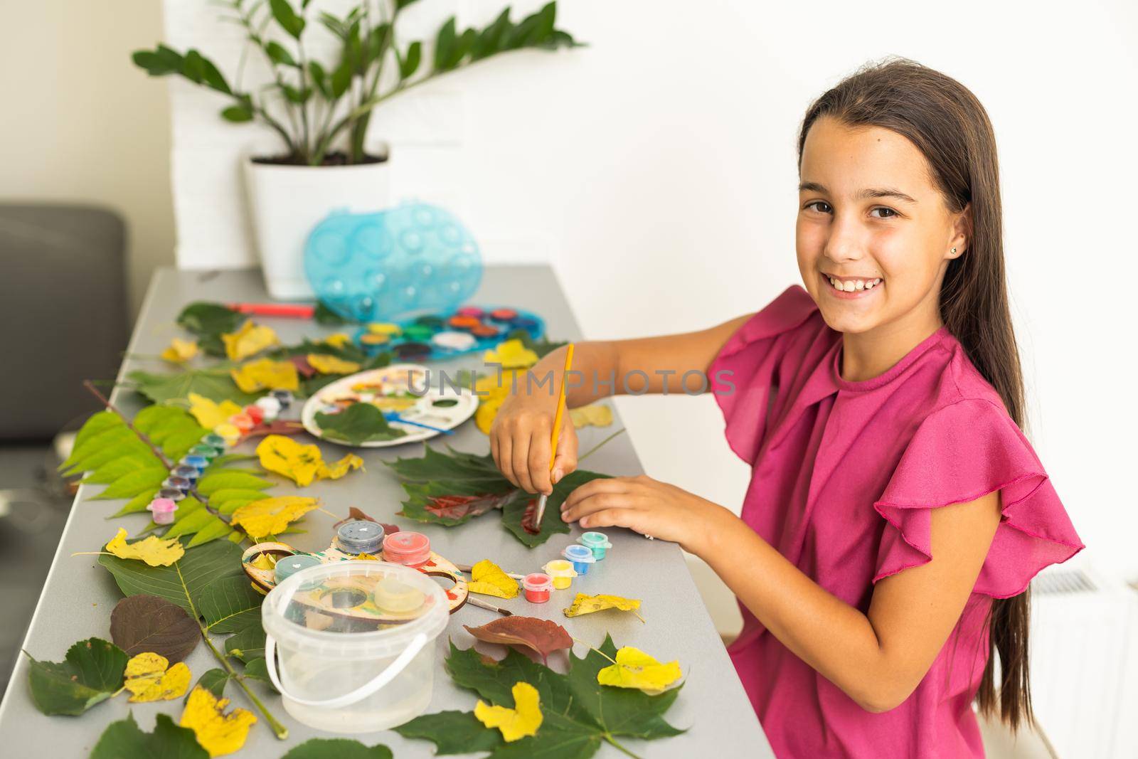 Little girl painting on autumn yellow leaves with gouache, kids arts, children creativity, autumn art. High quality photo