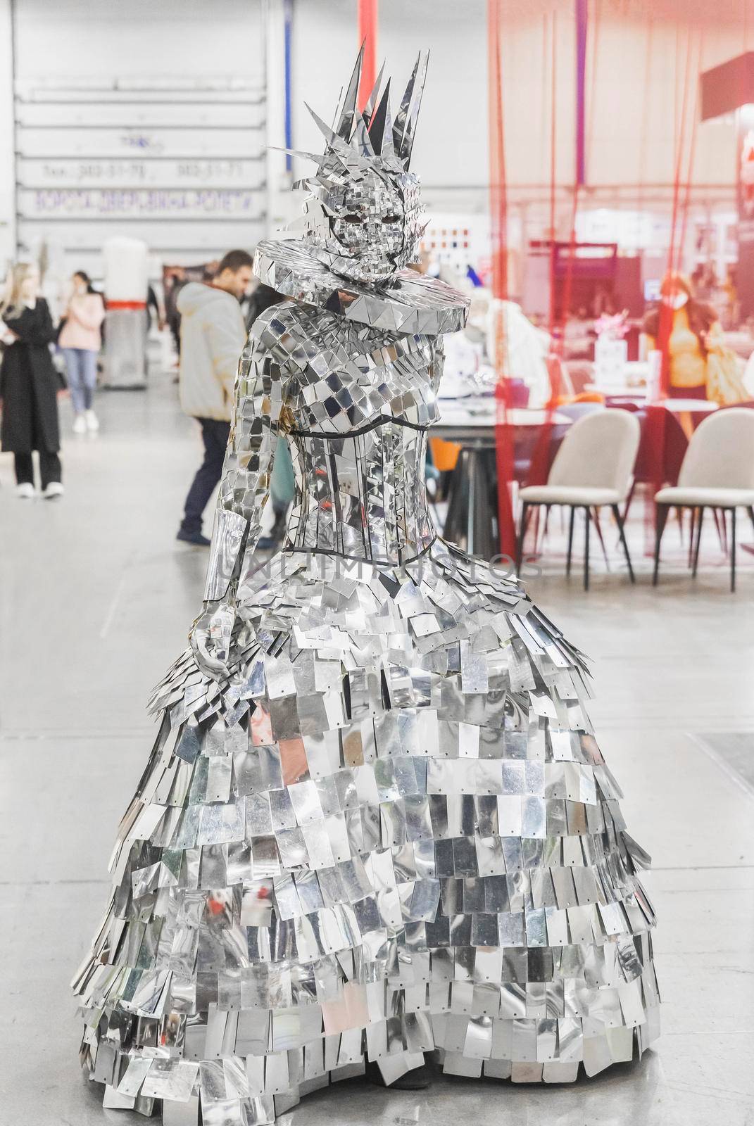 Kiev, Ukraine, October 2020: girl in a queen costume made of polished pieces of metal at the international furniture exhibition