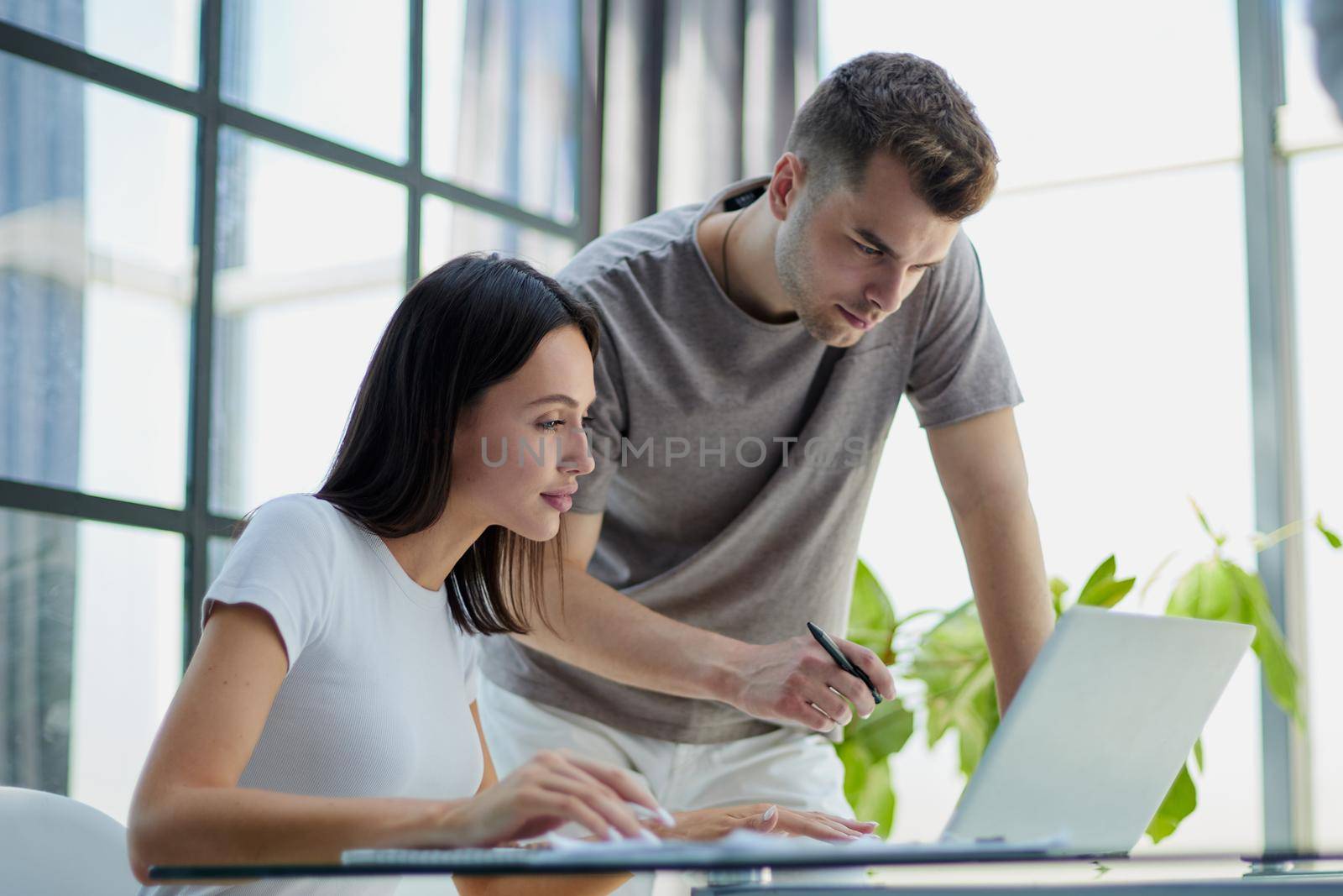 male ceo executive manager mentor giving consultation on financial operations to female colleague intern using laptop sitting in modern office