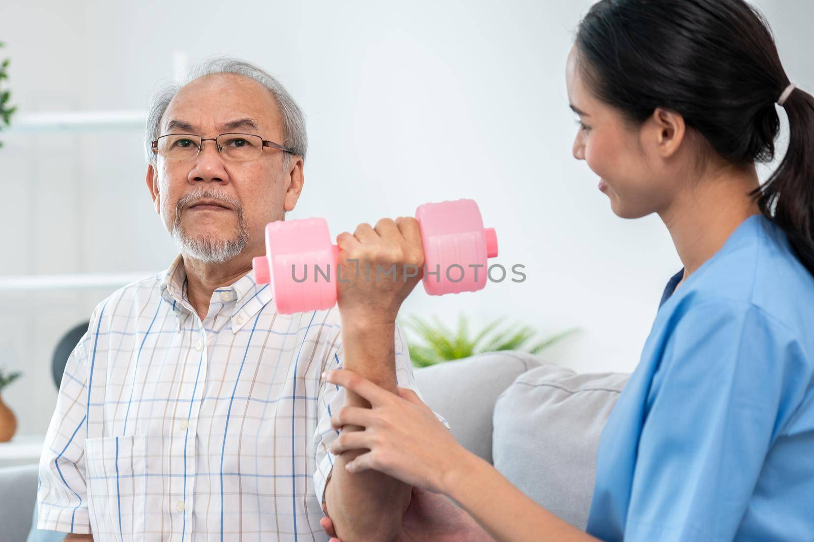 Unyielding senior patient doing physical therapy with the help of his caregiver. Senior physical therapy, physiotherapy treatment, nursing home for the elderly