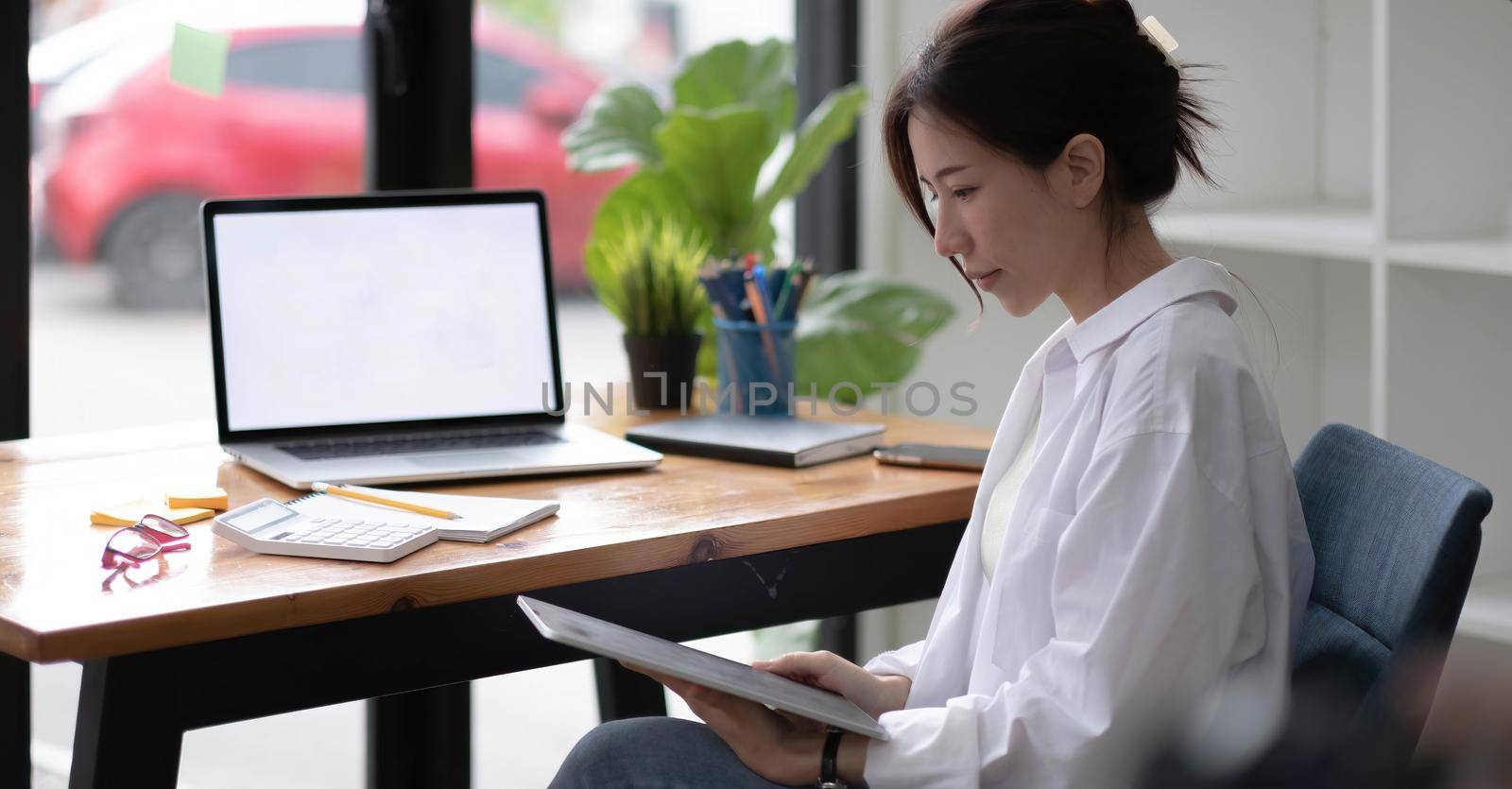 Portrait of a happy asian businesswoman working on tablet computer.