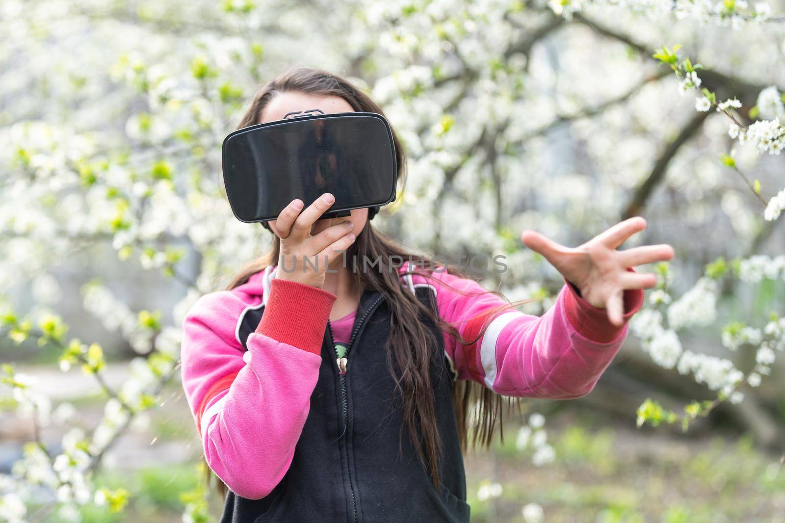Child with virtual reality headset sitting behind natrue outdoors at home