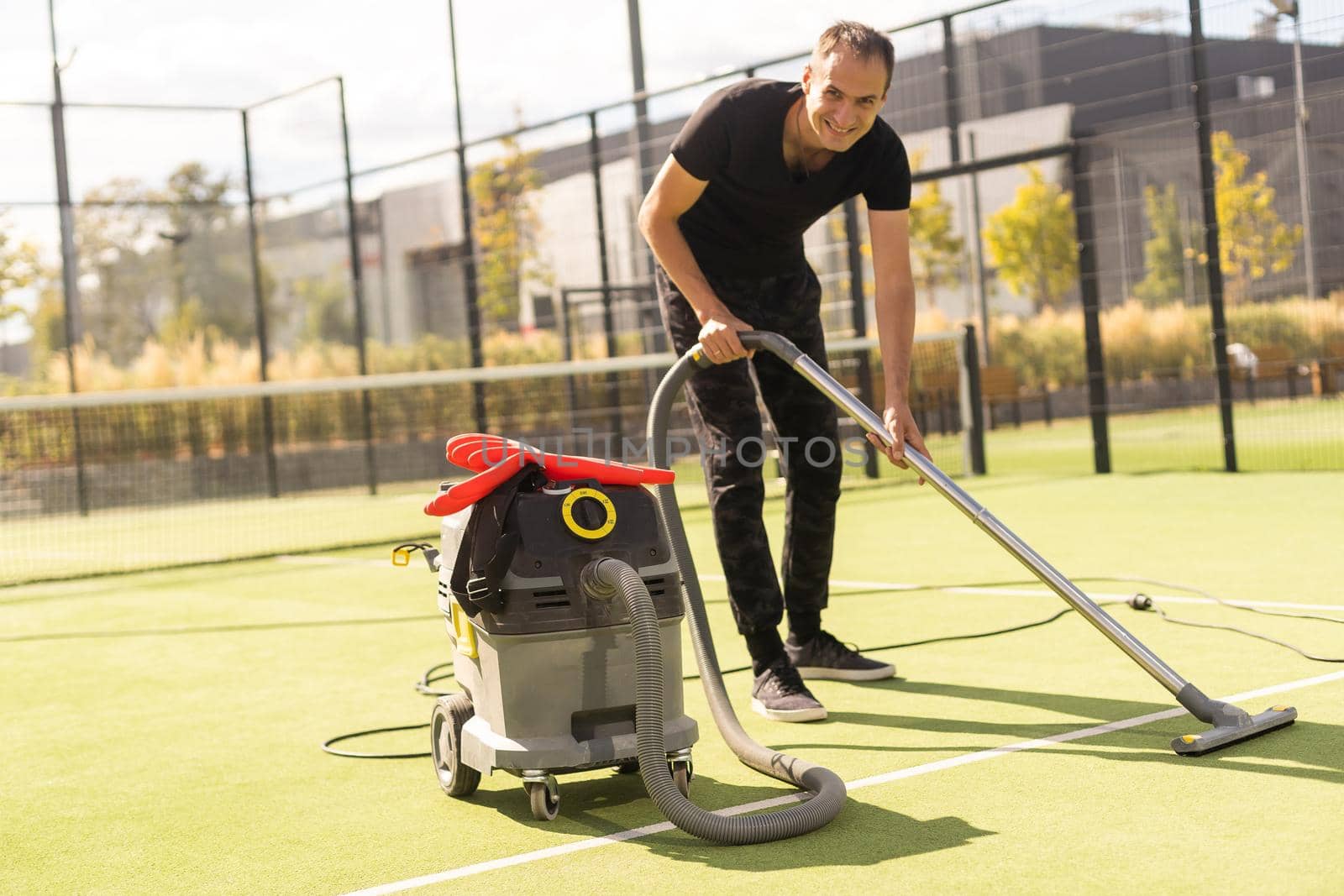 The boy cleaning tennis court clay surface after the match to prepare for the next match.