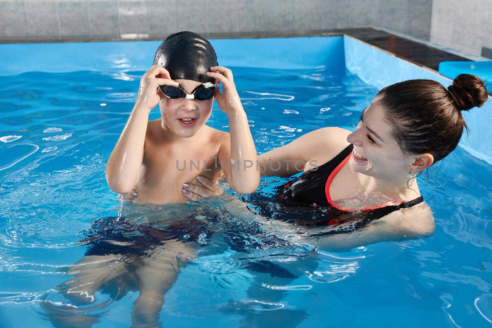 Boy learning to swim and dive in pool with teacher by Mariakray