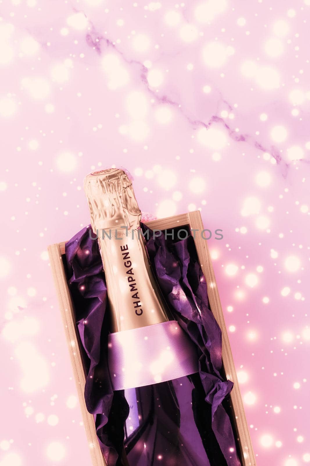 Celebration, drinks and branding concept - Champagne bottle and gift box on pink holiday glitter, New Years, Christmas, Valentines Day, winter present and luxury product packaging for beverage brand