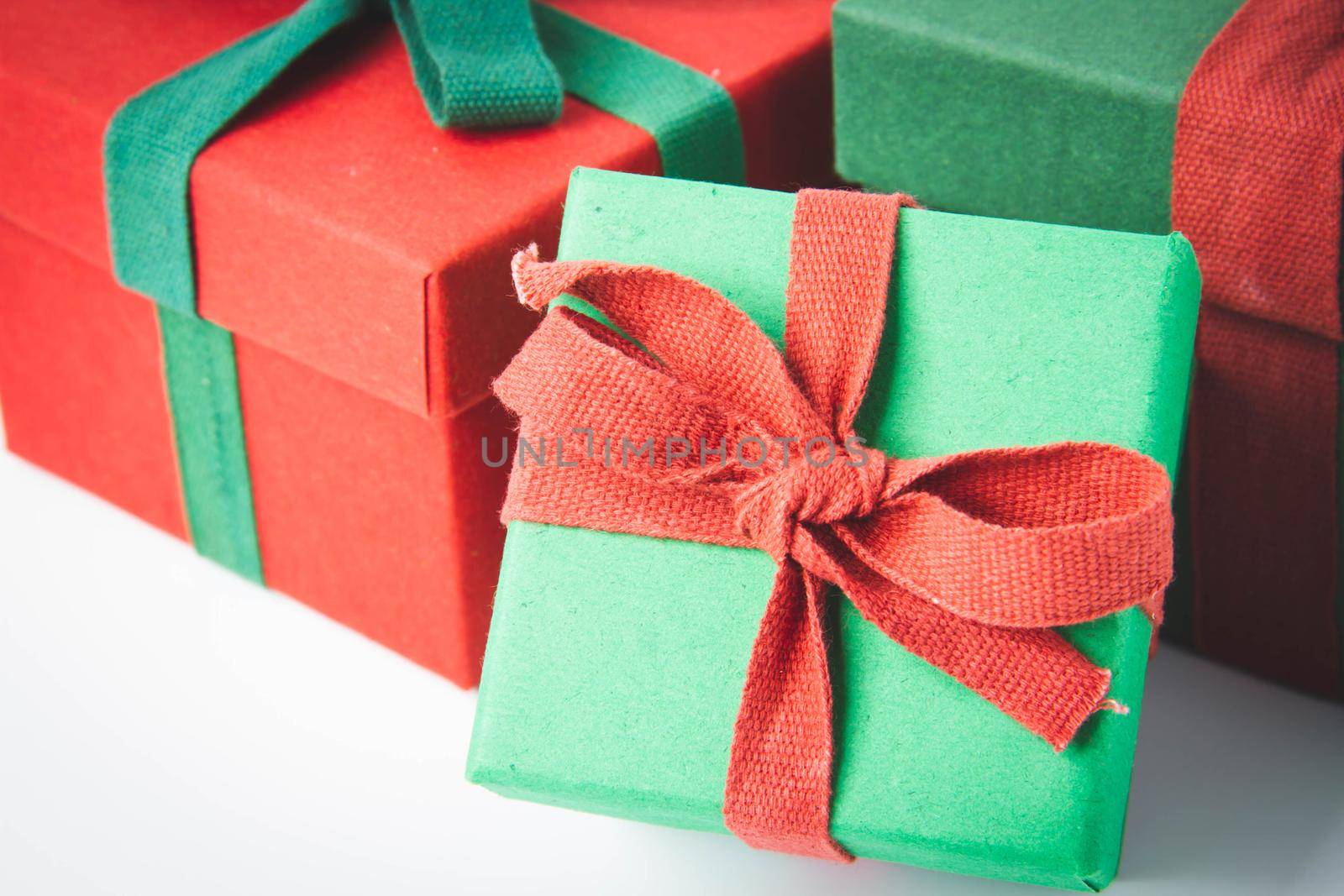 Present. Gift box with a bow. New Year's surprise. Red and green box with a gift. On a white background, top view. Close-up. Tied with a beautiful ribbon for gifting. Under the tree.