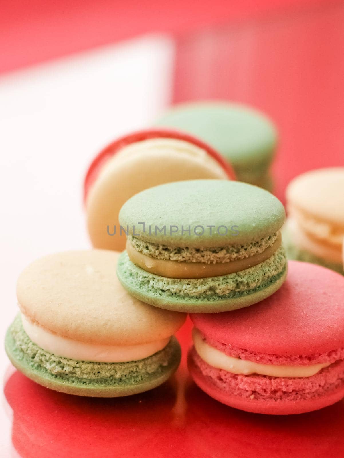 Pastry, bakery and branding concept - French macaroons on fruity red background, parisian chic cafe dessert, sweet food and cake macaron for luxury confectionery brand, holiday backdrop design
