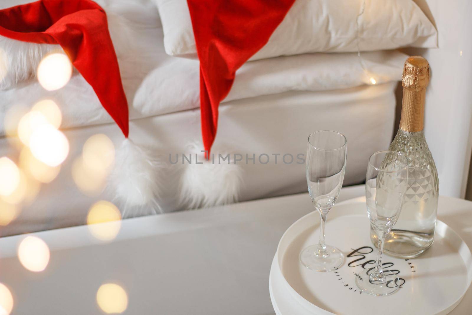 Two glasses and a bottle of champagne in a hotel room with Christmas decor. The concept of celebrating the new year in travel and hotel. by lara29