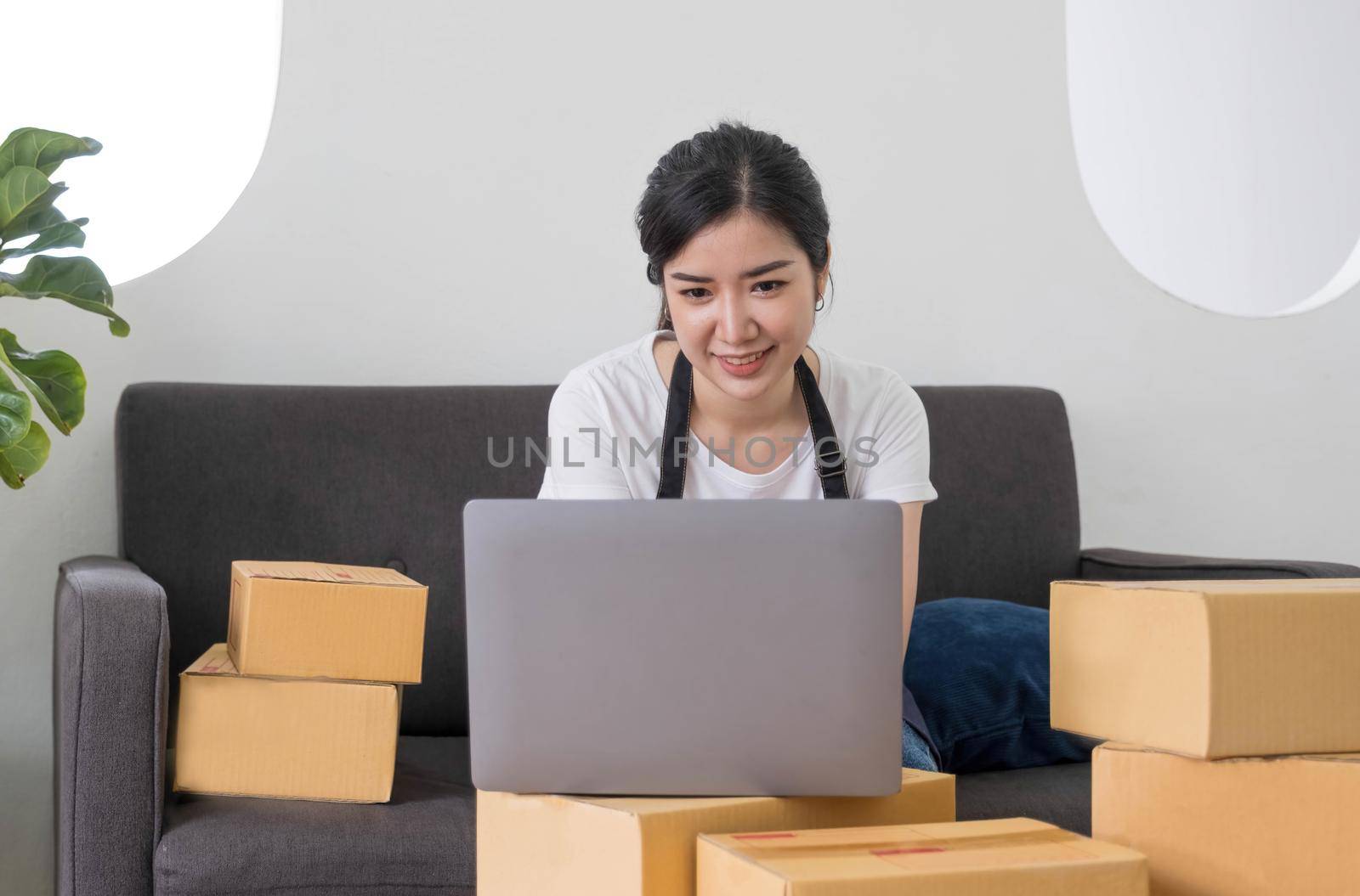 Starting Small business entrepreneur freelance,Portrait young woman working at home office, BOX,smartphone,laptop, online, marketing, packaging, delivery, SME, e-commerce concept by wichayada