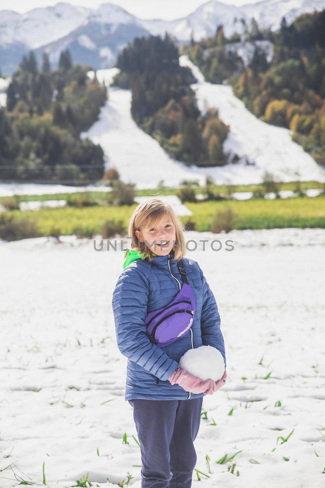 blonde girl makes a snowman in Slovenia in the Alps.