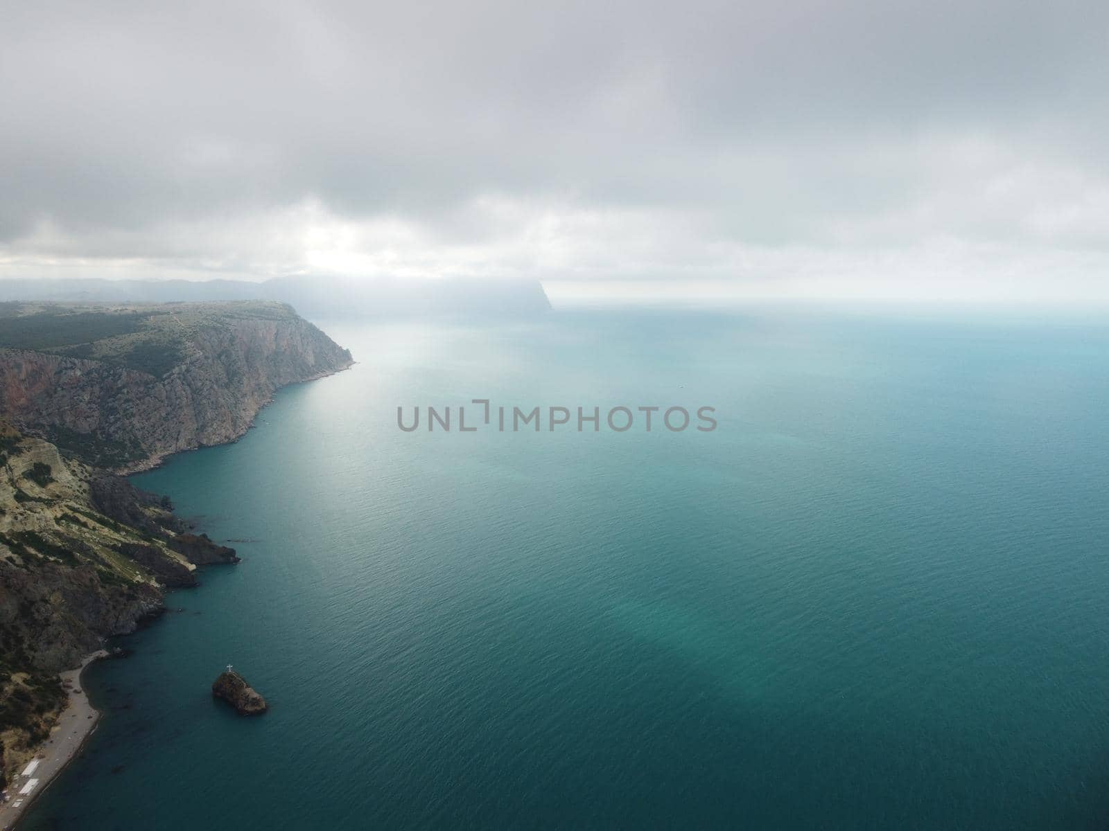 Aerial view from above on calm azure sea and volcanic rocky shores. Small waves on water surface in motion blur. Nature summer ocean sea beach background. Nobody. Holiday, vacation and travel concept by panophotograph