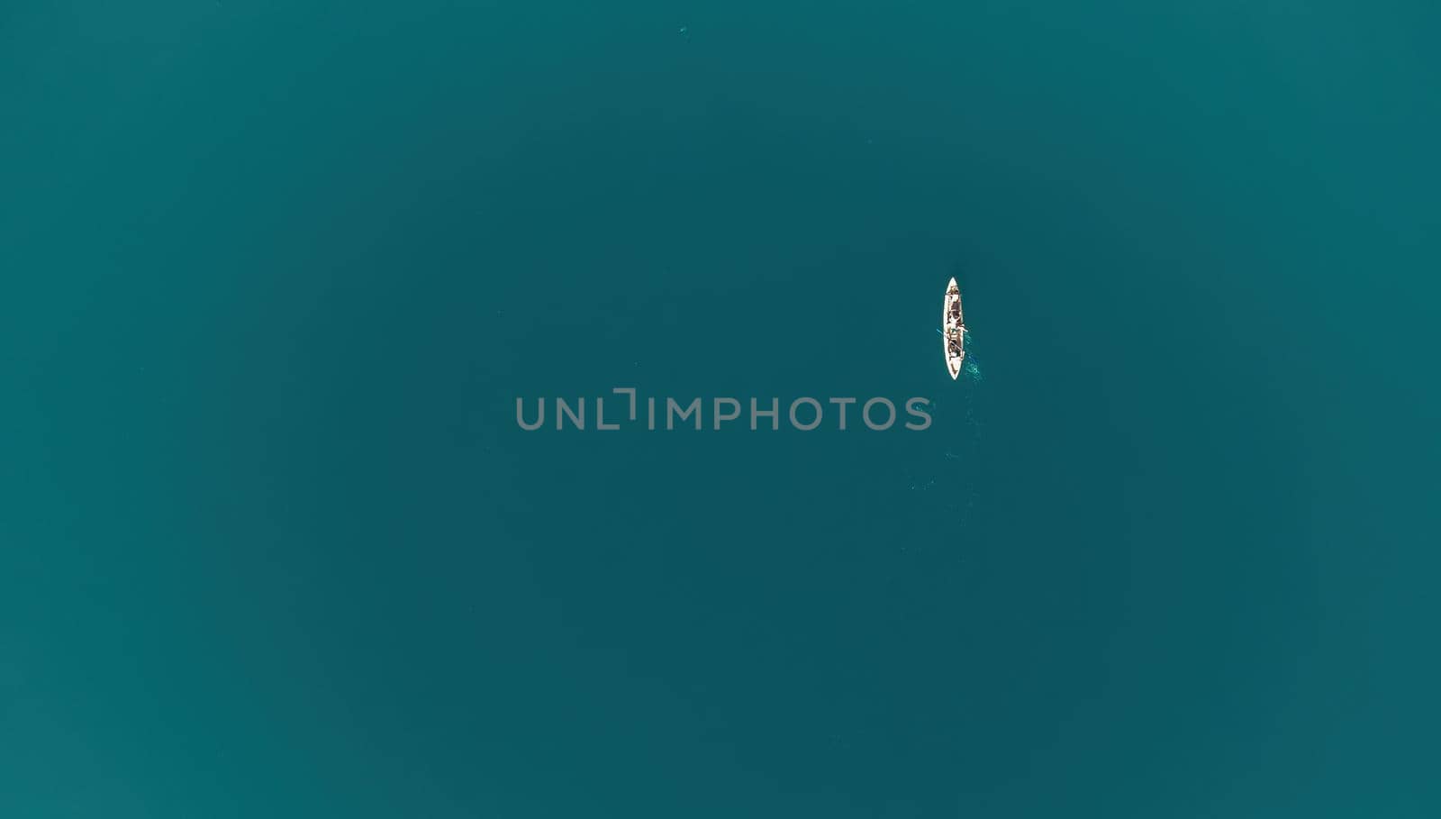 Aerial top view of a family kayaking in calm blue sea. Unrecognizable woman, man and childrens. Kayak on turquoise sea water during warm day at sea. Summer holiday vacation and travel concept by panophotograph