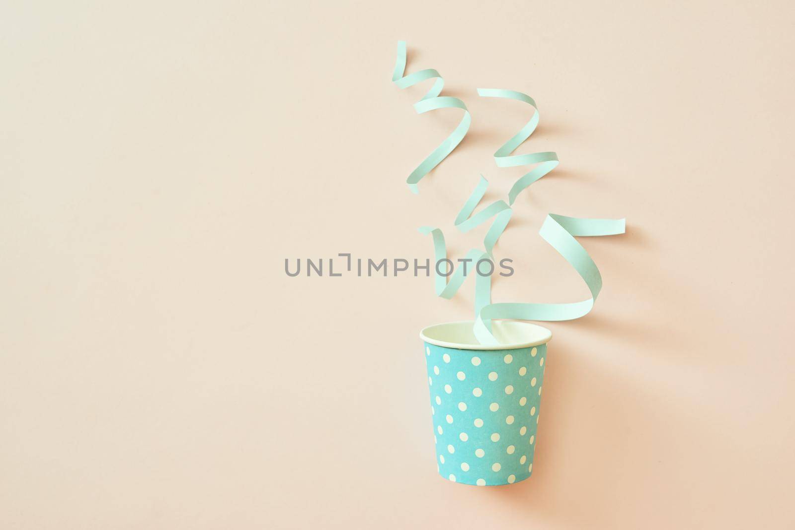 Celebration concept. Paper cup with confetti on a beige background. 