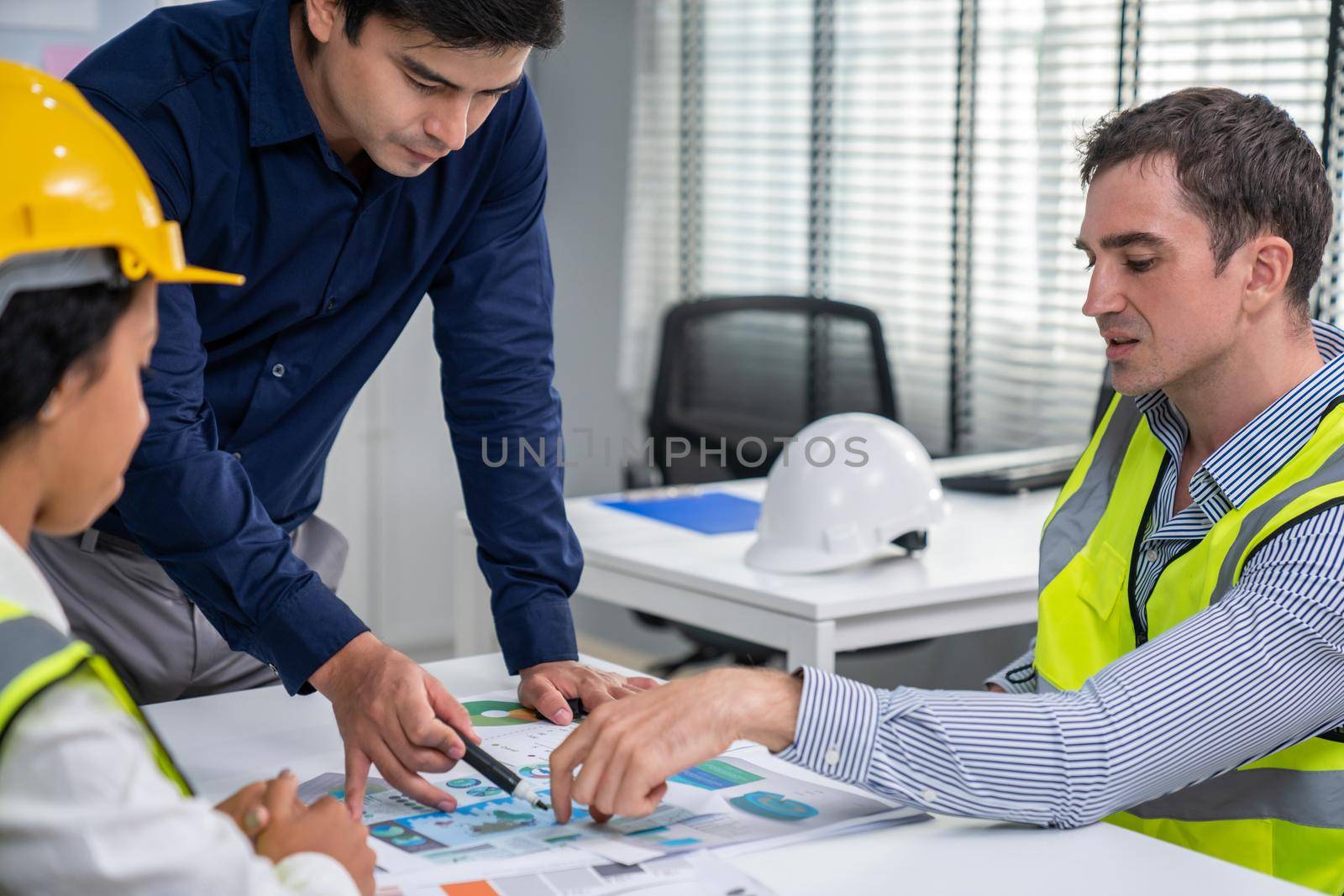 Engineers and competent employer discussing plans and blueprints together with tablet in the office. Concept of team contribution of ideas for engineering project.