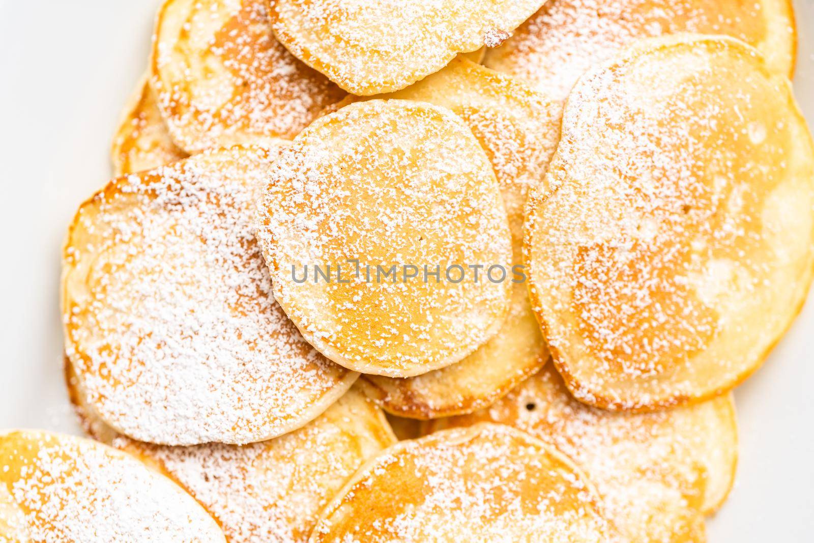 Flat lay. Freshly made small pancakes on a kefir base garnished with powdered sugar.