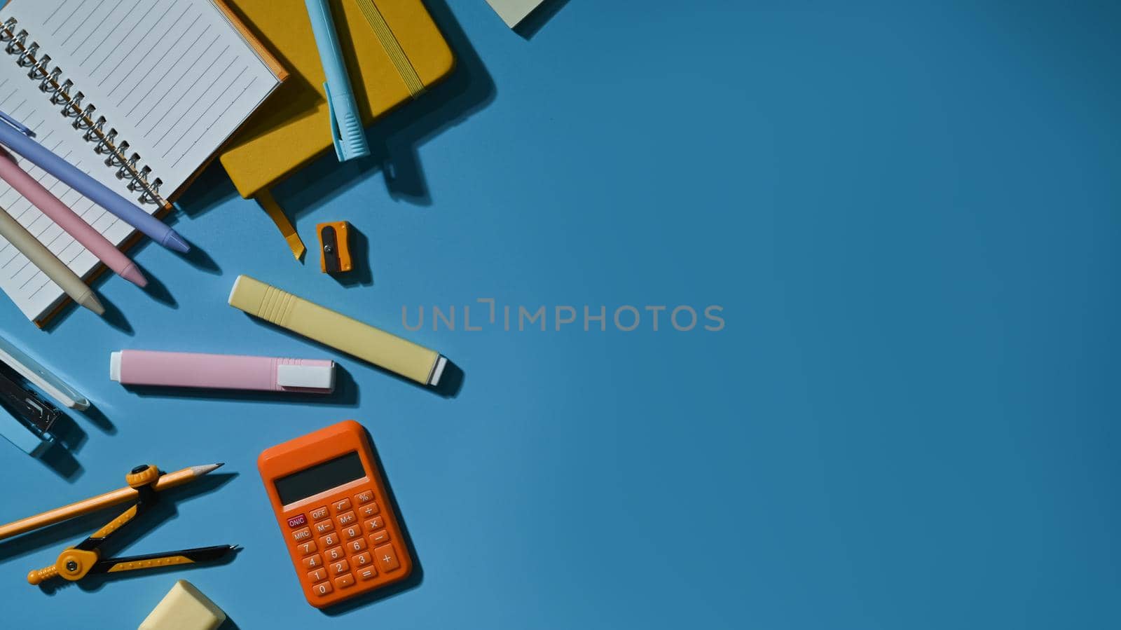 Various school supplies on a blue background with copy space ready for your design. Top view, Flat lay.