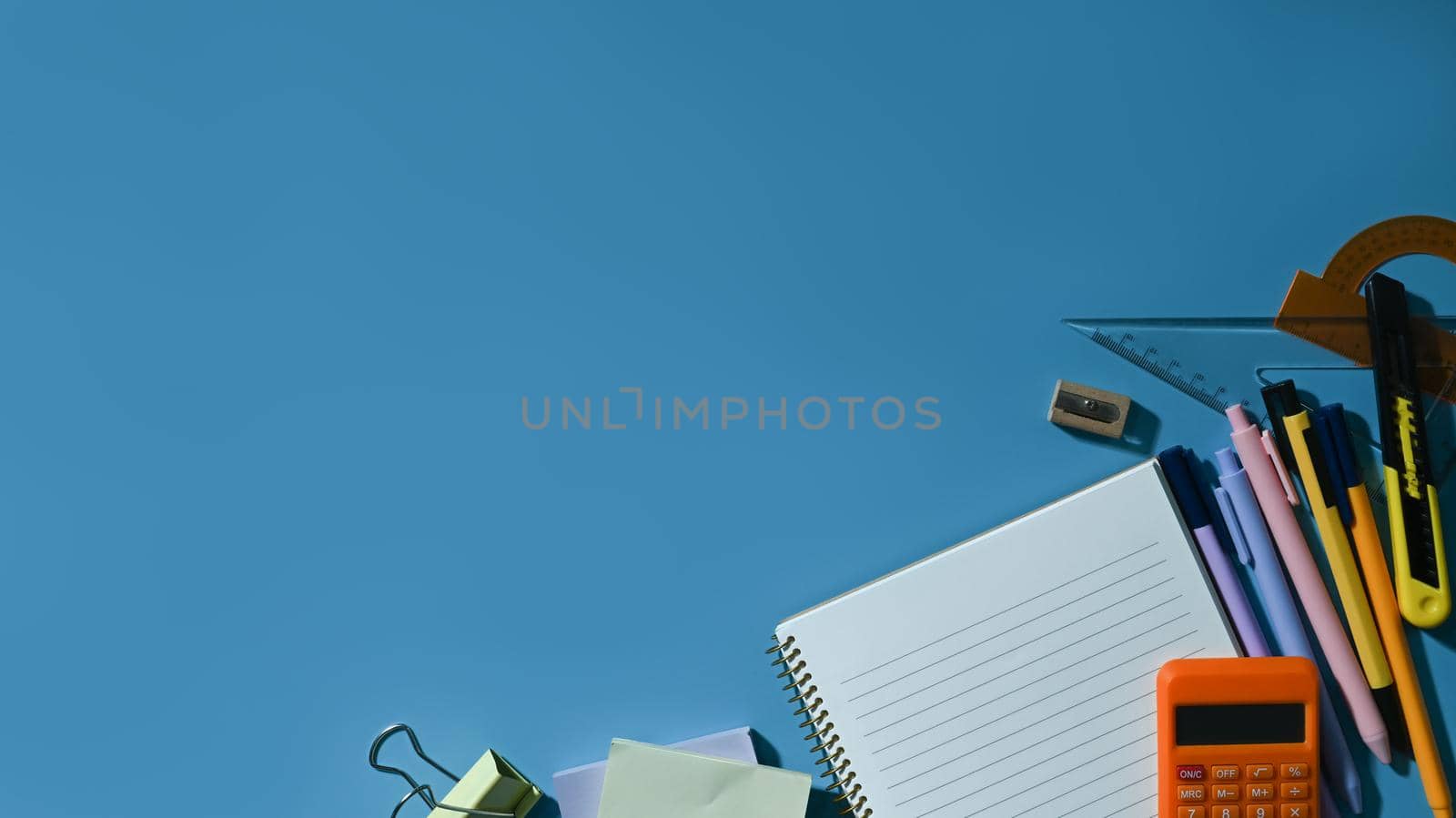 Flat lay school stationery on blue background with empty copy space. Back to school concept.