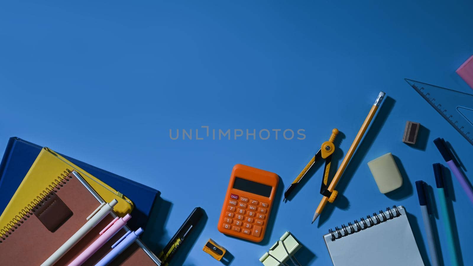 Top view of various school supplies on a blue background with empty space ready for your design by prathanchorruangsak
