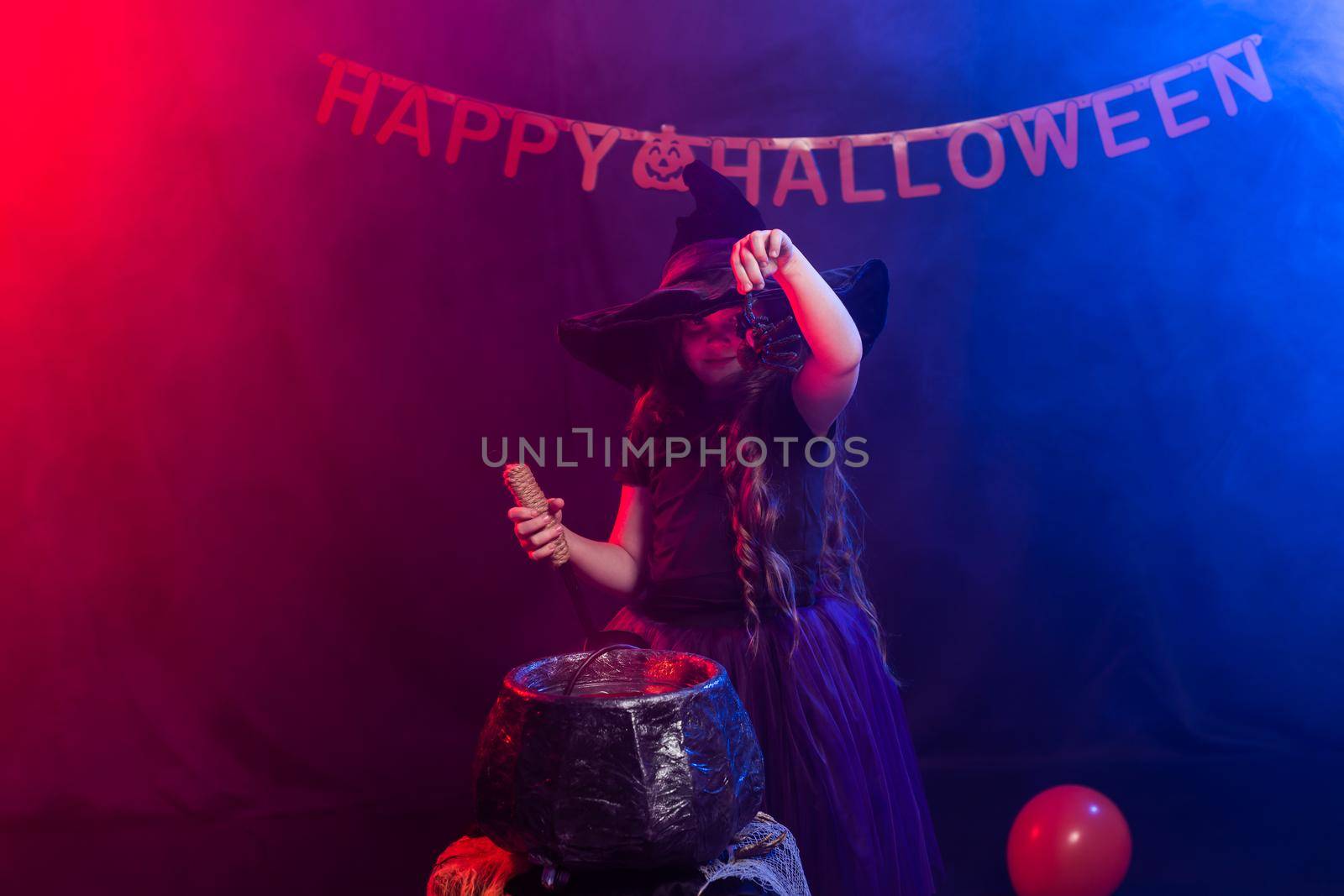 Funny child girl in witch costume for Halloween with pumpkin Jack
