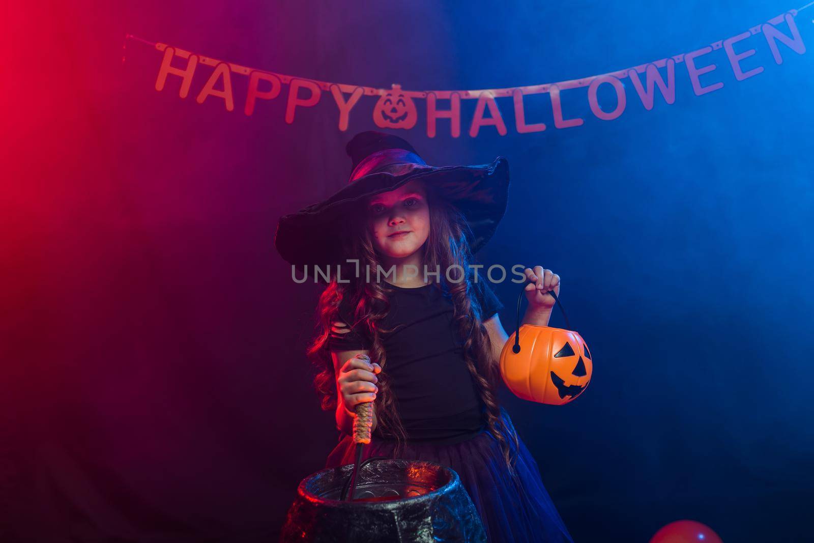 Funny child girl in witch costume for Halloween with pumpkin Jack