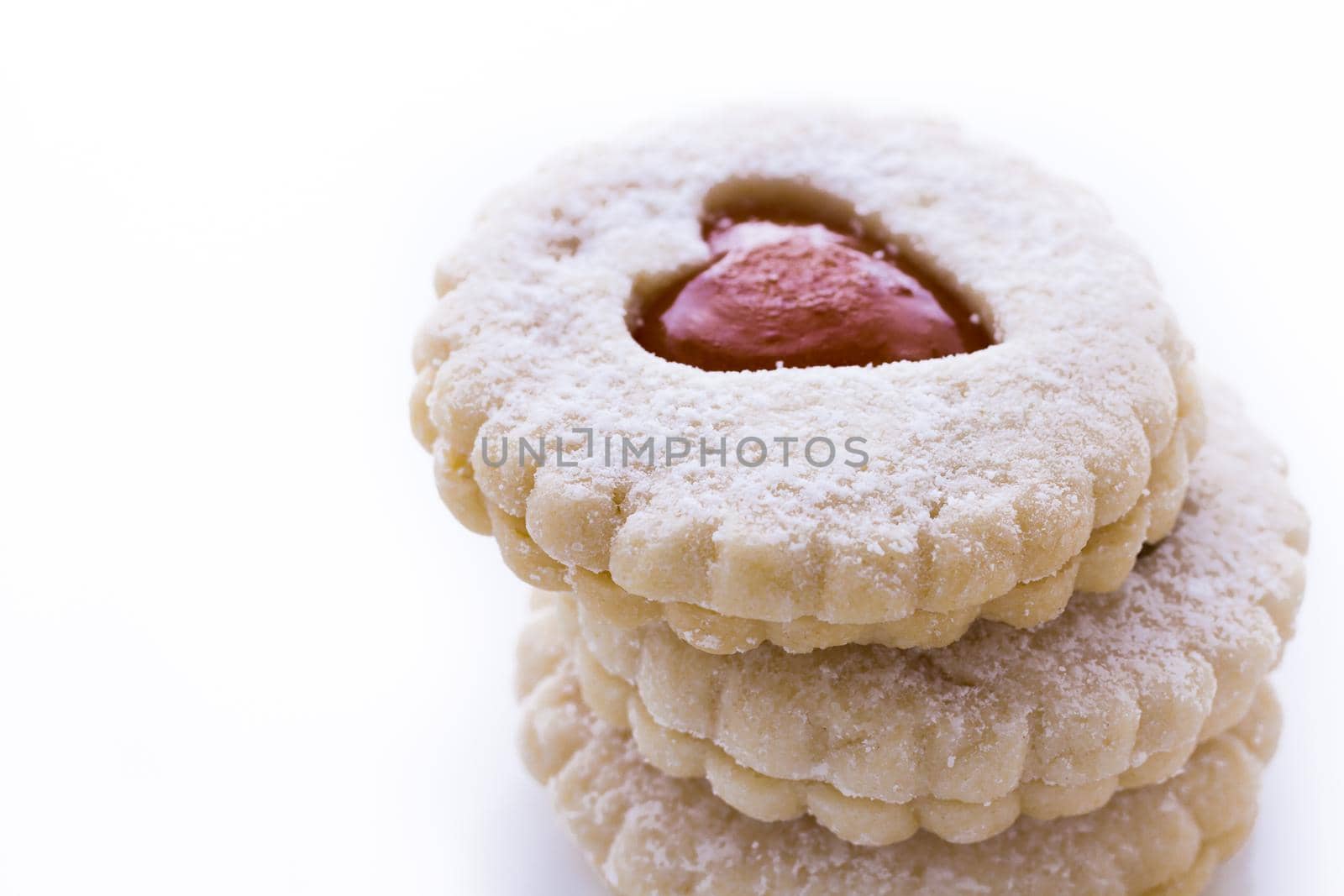 Linzer Torte cookies on white background with powdered sugar sprinkled on top.