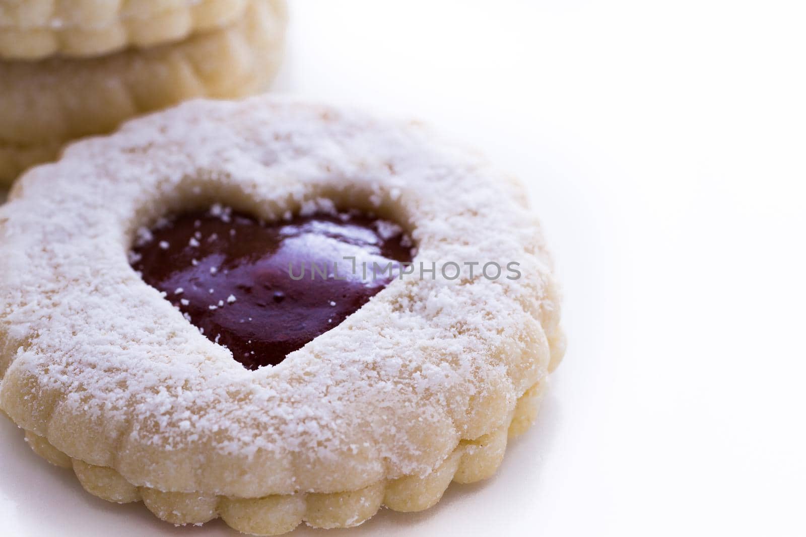 Linzer Torte cookies on white background with powdered sugar sprinkled on top.