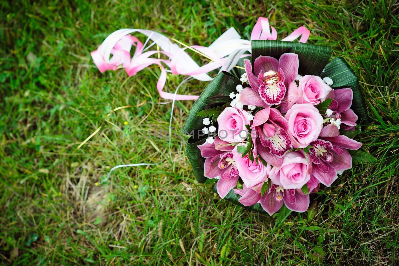 Bridal wedding bouquet of flowers. Wedding bouquet of pink roses lying on a grass.