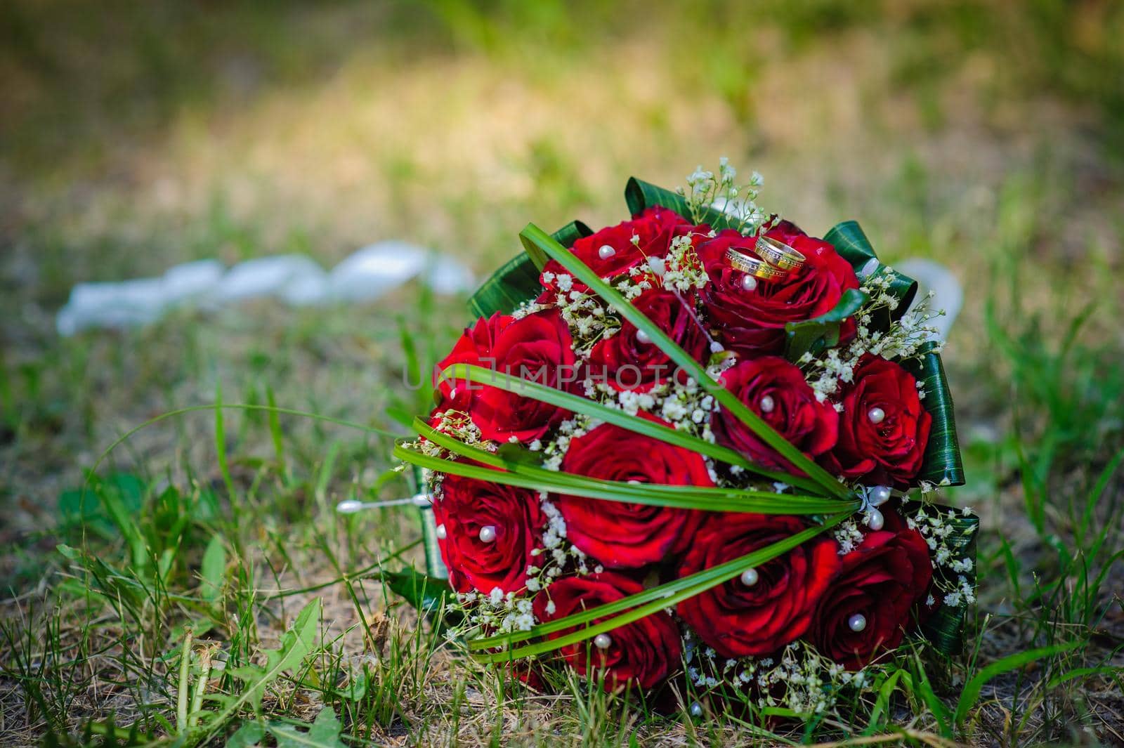 Bridal wedding bouquet of flowers. Wedding bouquet of red roses lying on a grass.