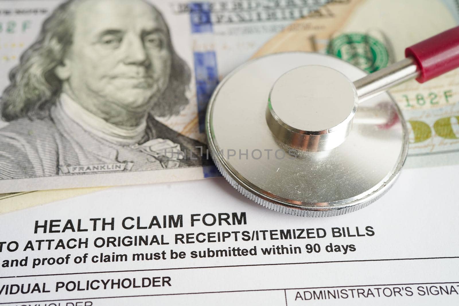 Health claim form with stethoscope and US dollar banknotes, insurance accident medical concept.