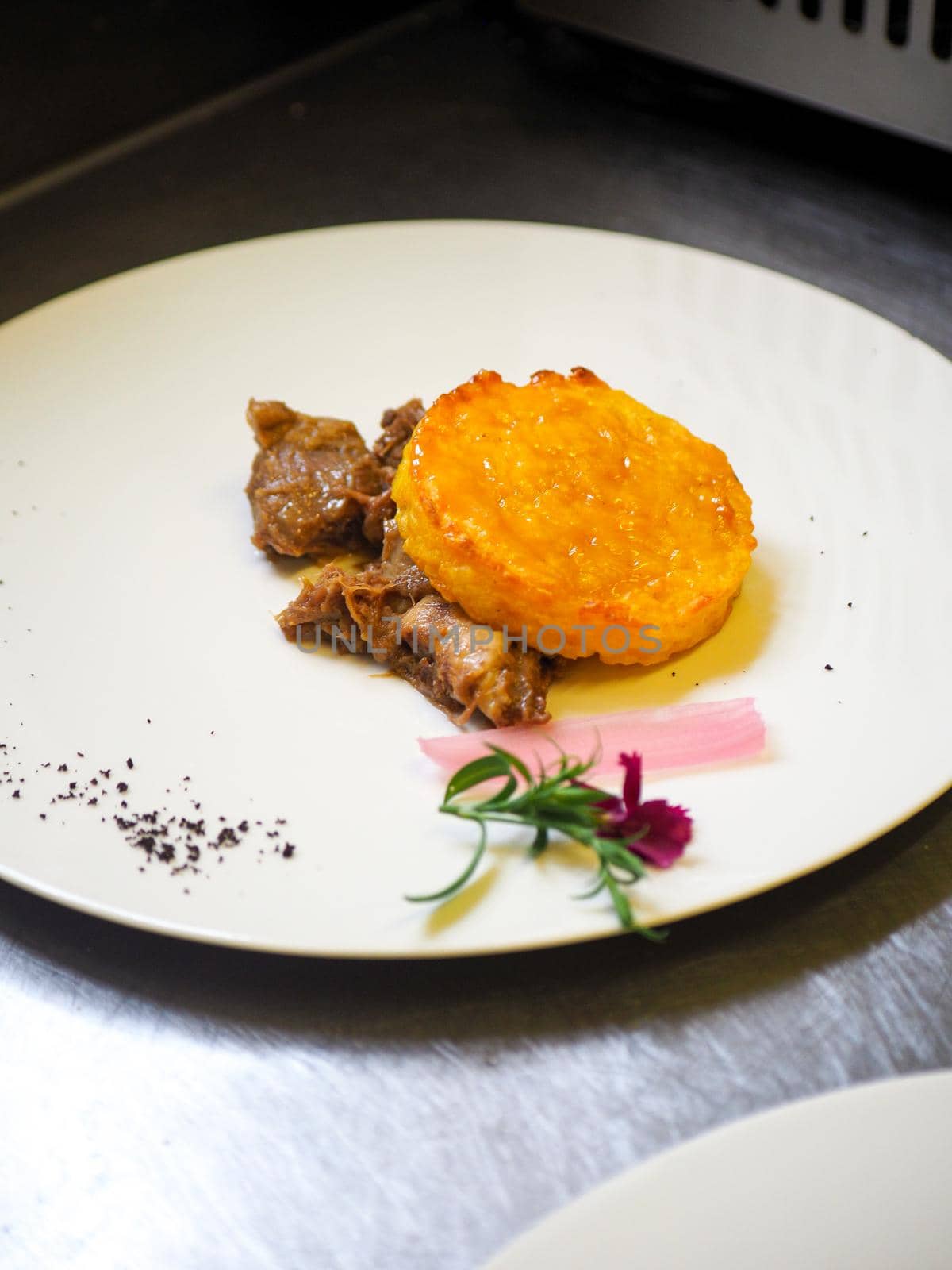 staff plating a modern second course meat decorated dish - line of prepared food for party