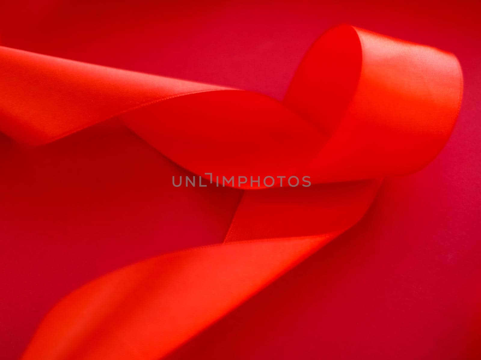 Branding, holidays and luxe brands concept - Abstract curly silk ribbon on red background, exclusive luxury brand design for holiday sale product promotion and glamour art invitation card backdrop