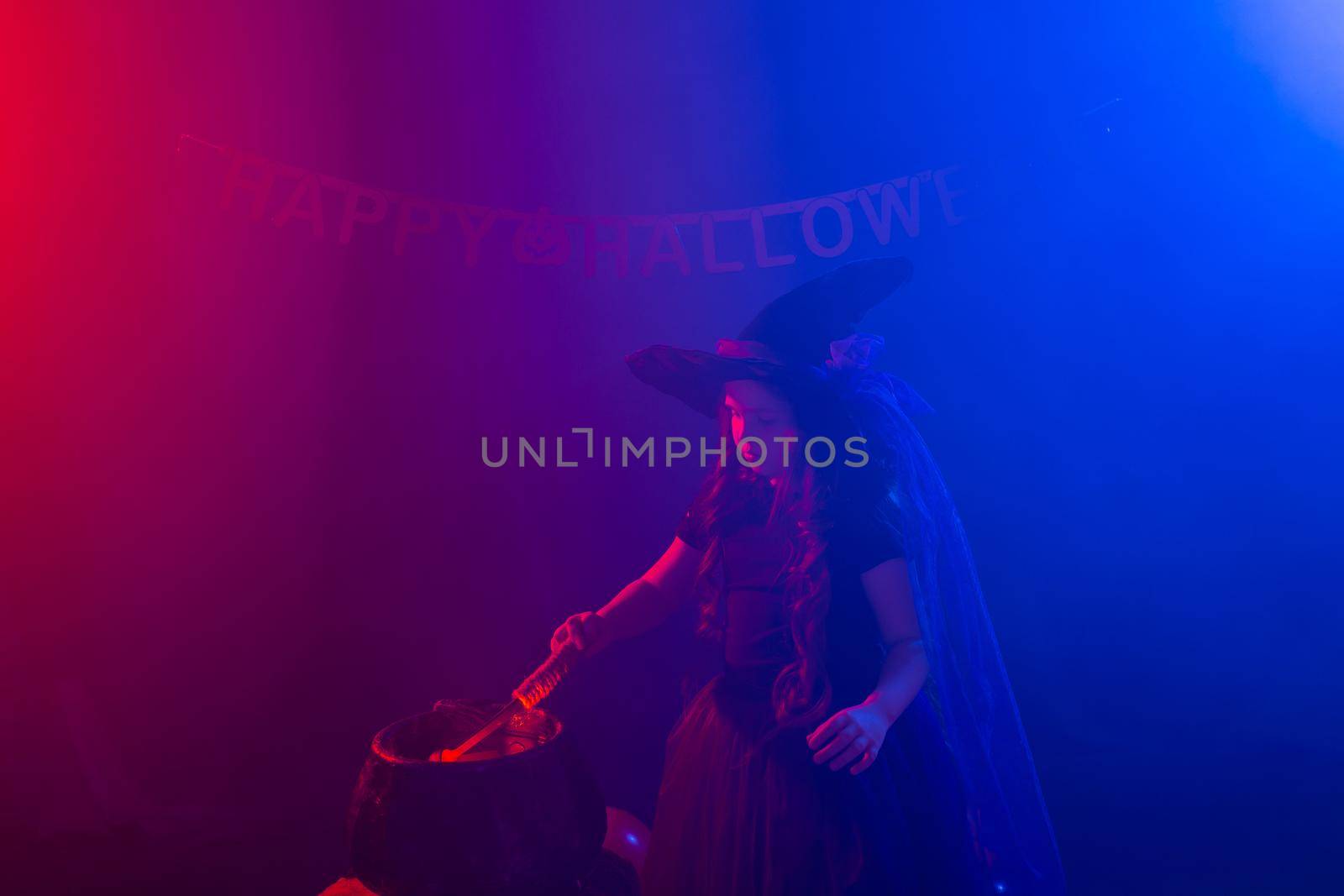 Child girl witch preparing a potion in the cauldron at halloween holidays. Copy space. by Satura86