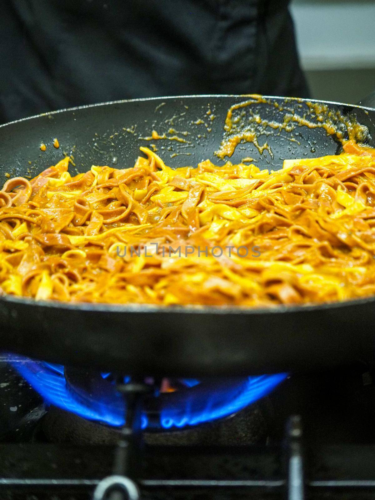 mixing pasta with sauce in a big professional used professional pan