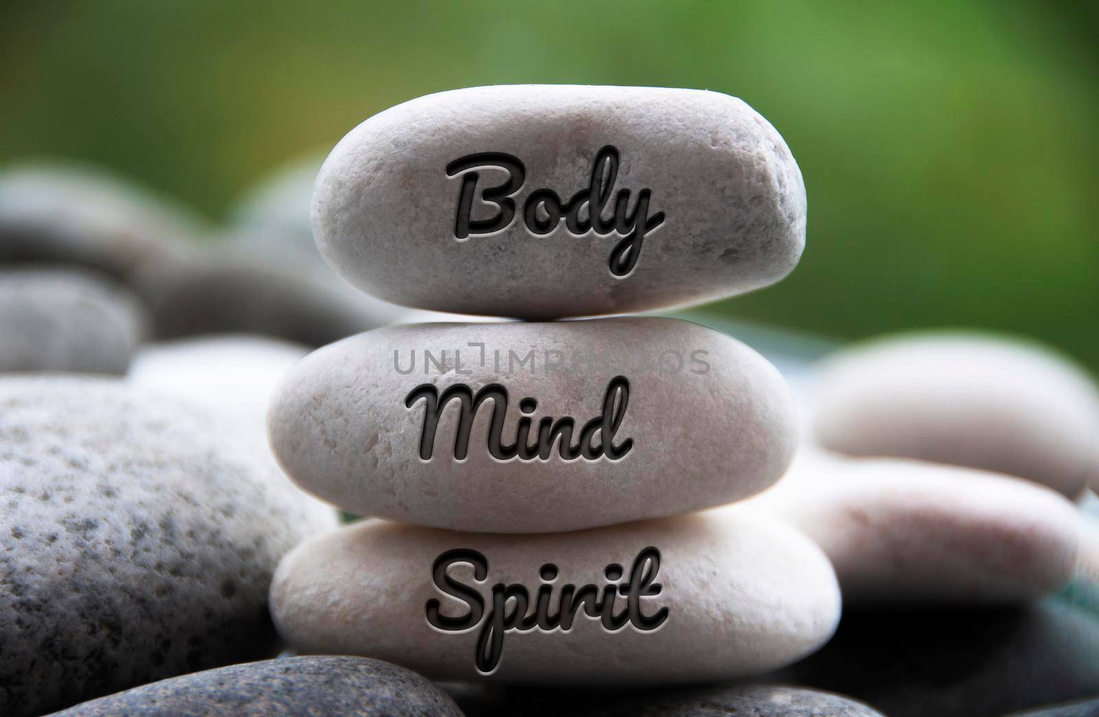 Body, Mind and Spirit words engraved on zen stones. Copy space and zen concept.