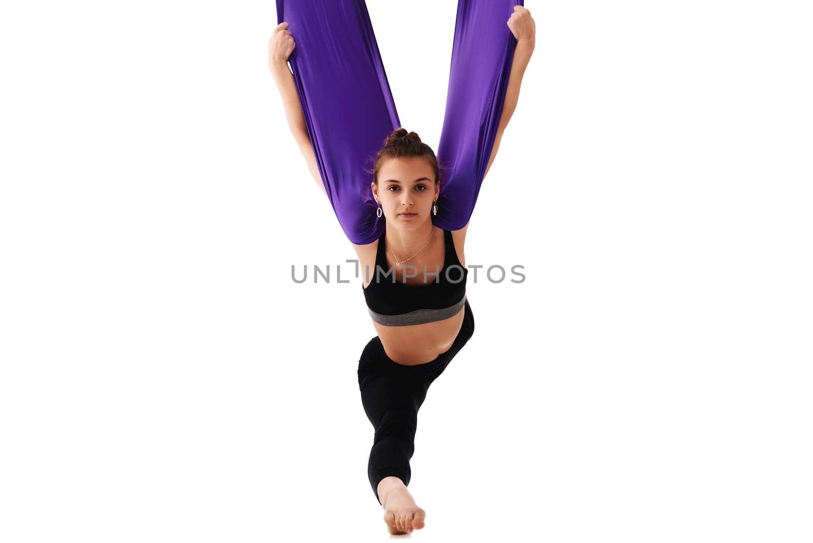Young beautiful woman practice in Fly yoga. fitness trainer in Purple hammock. Aero yoga in hammocks, anti gravity. Girl hang in sports hammock. Stretching, balance, exercise and a healthy lifestyle.