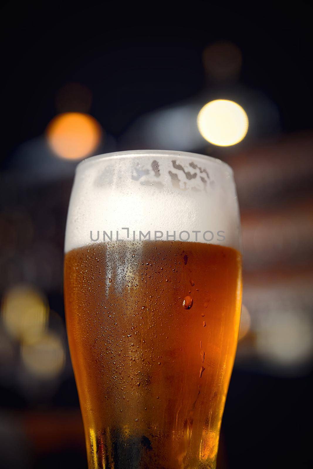 Glass of beer on a table in a bar on blurred bokeh background.