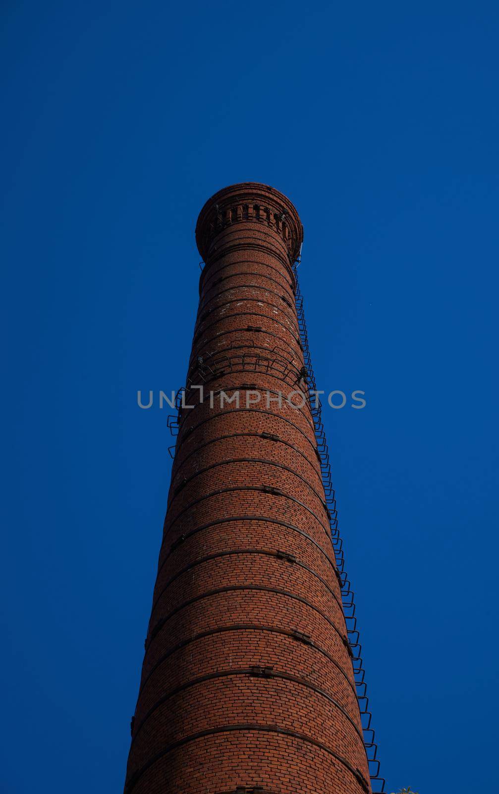 tall chimney old red bricks in an old factory. smoke stack An old brick chimney against a blue sky.