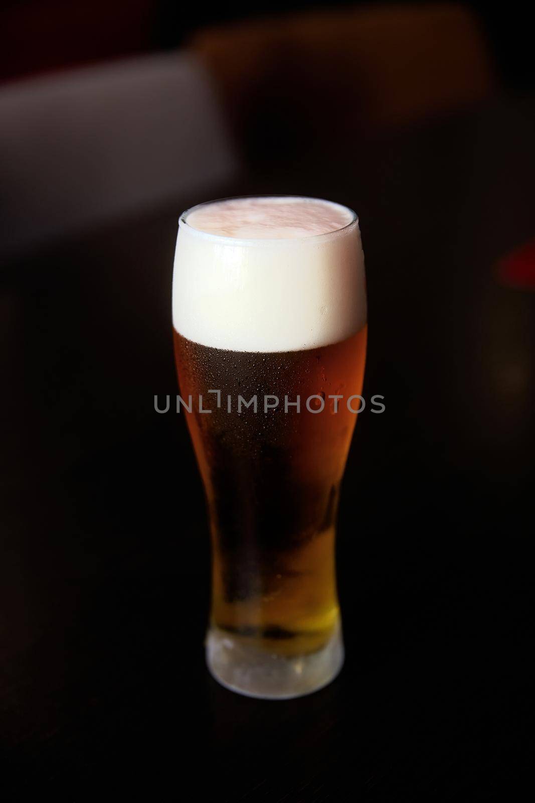 Fresh cold beer, glass of beer on a table in a bar on blurred bokeh background.