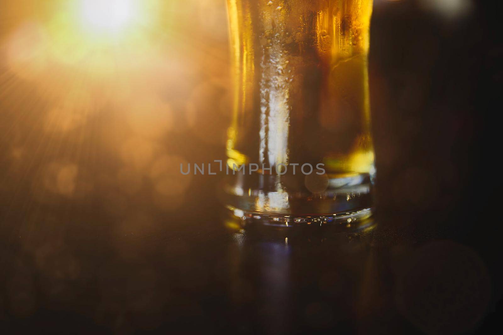 Glass of beer on a table in a bar on blurred bokeh background.