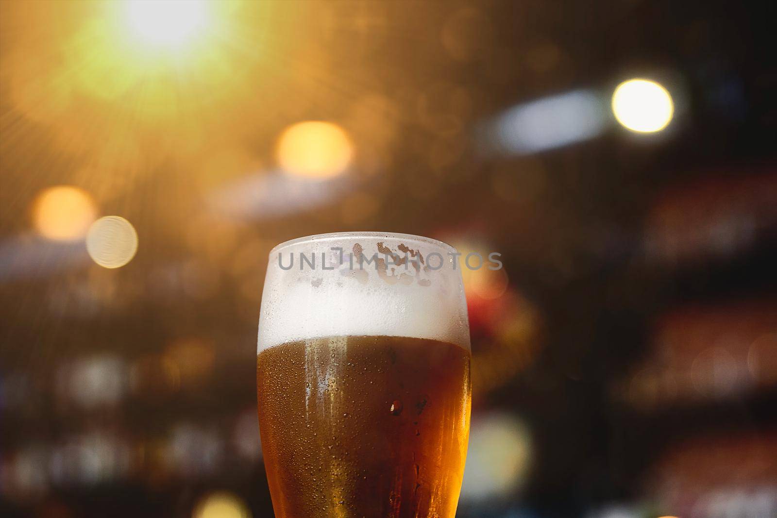 Glass of beer on a table in a bar on blurred bokeh background.