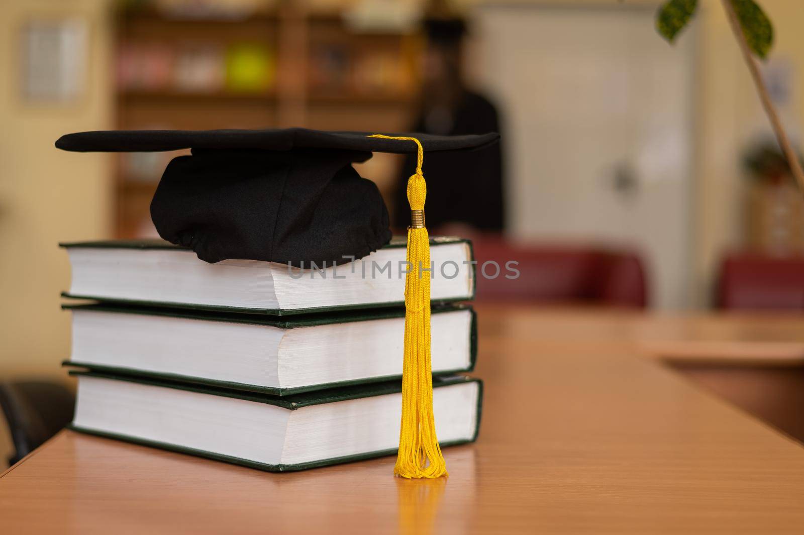 Graduation cap on a stack of books in the library. by mrwed54