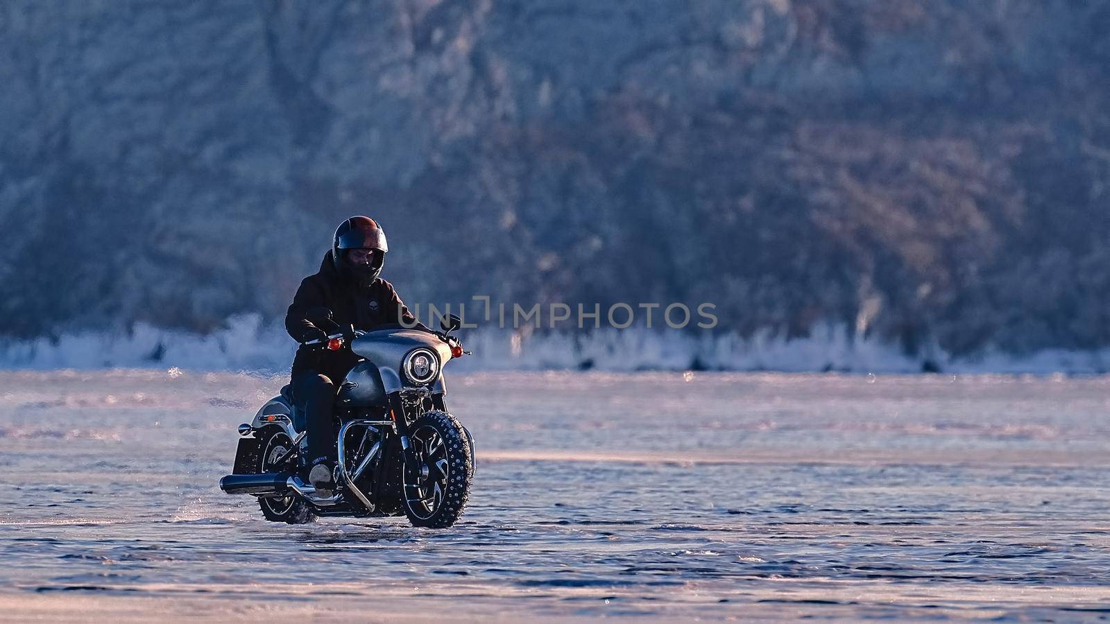 Biker riding on motorcycle Harley Davidson on a frozen lake. 03.08.2019 BAIKAL LAKE, OLKHON ISLAND, IRKUTSK REGION, RUSSIA