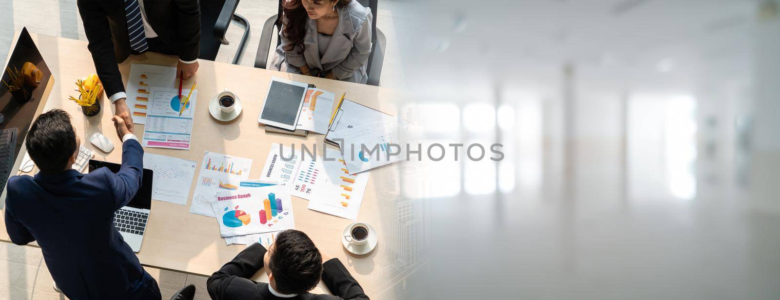 Group business people handshake at meeting table in widen view in office together with confident shot from top view . Young businessman and businesswoman workers express agreement of investment deal.